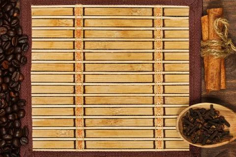 Bamboo mat with frame of coffee beans and condiments Stock Photos