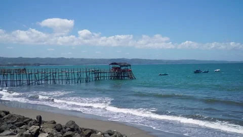 A bamboo pier extends into the turquoise-blue sea beneath a clear sky. Stock Footage 347915853