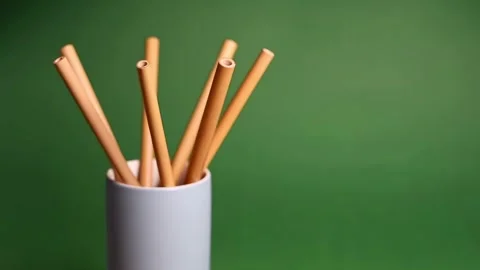 Bamboo straws rotating in white cup on green background for eco friendly li.. Stock Footage 339766645
