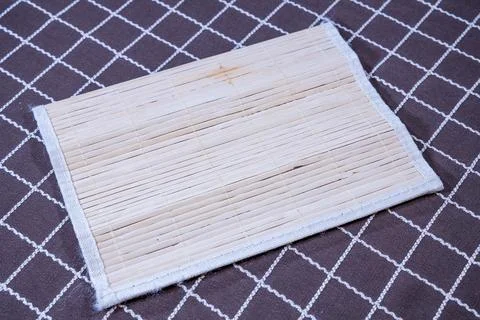 Bamboo sushi rolling mat on patterned cloth Stock Photos