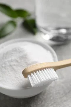 Bamboo toothbrush, green leaf and bowl of baking soda on grey table, closeup Stock Photos