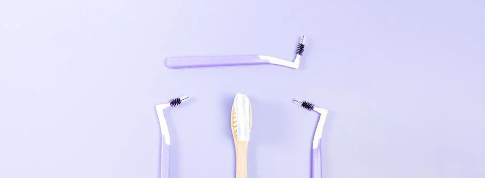 Bamboo toothbrush with toothpaste and three small toothbrushes on a soft lila Stock Photos