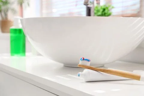 Bamboo toothbrush with toothpaste on bathroom countertop, oral hygiene and su Stock Photos