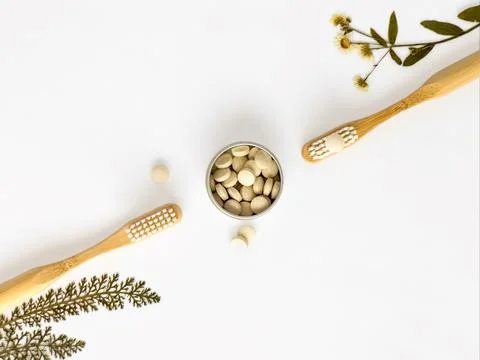 Bamboo toothbrushes and toothpaste in tablets, dried flowers. Flatly on white Stock Photos