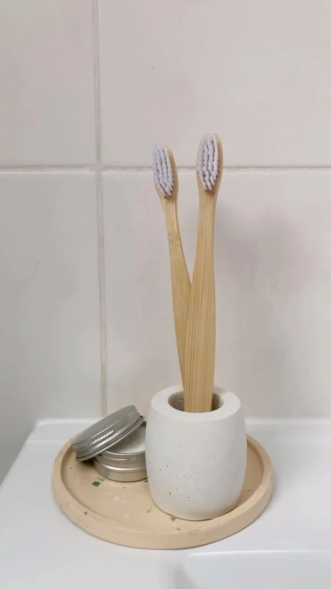 Bamboo toothbrushes in a concrete stand. Toothpaste powder. 4K vertical video. Stock Footage 261700916