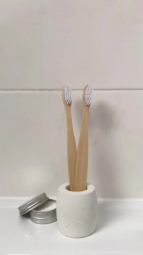 Bamboo toothbrushes in a concrete stand. Toothpaste powder. 4K vertical video. Stock Footage 261954716