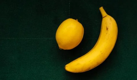 Banana and lemon on emerald background, healthy food Stock Photos