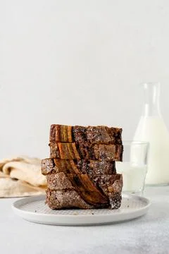 Banana bread cut into slices in stack with glass of milk on plain gray concre Stockfoto's