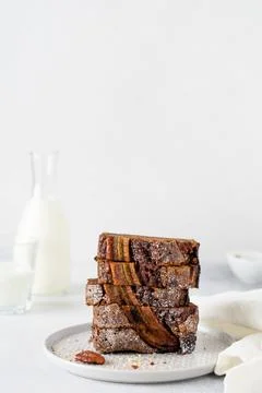 Banana bread cut into slices in stack with glass of milk on plain gray concre 스톡 사진