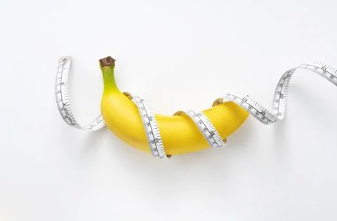 A banana with a measuring tape wrapped around a white background Stock Photos
