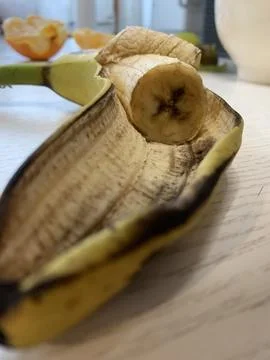 A banana is placed on a table, showcasing its textured peel and a distinct cut Stock Photos