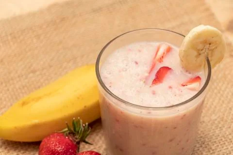 Banana Strawberry Milkshake. Glass cup on a wooden background. Homemade. Stock Photos