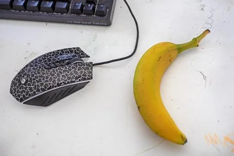 Banana on the table near the computer with a computer mouse. snack Stock Photos