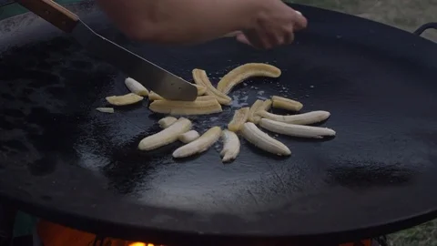 Bananas being placed on griddle while chef pokes with spatula Stock Footage 108564815