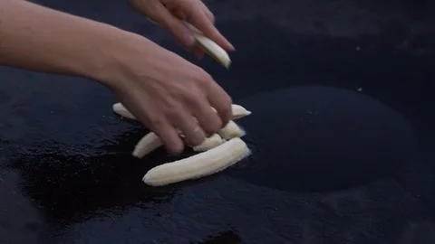Bananas being placed on sizzling griddle Stock Footage 108564580