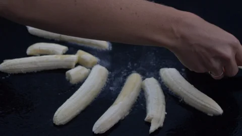 Bananas being placed on sizzling griddle Stock Footage 108564646