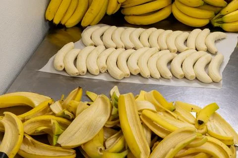 Bananas placed on a table in a kitchen with more bananas in the background .. Stock Photos