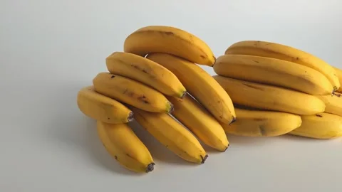 Bananas stacked in groups on a plain white background at different angles Video stock 338120717