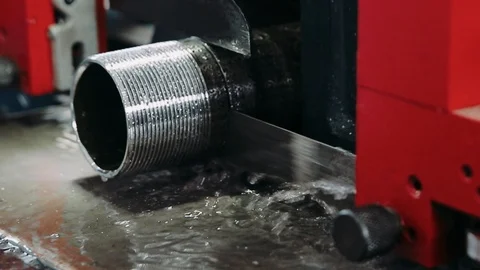 The band saw machine cutting raw metals rods the with the coolant fluid. The Stock Footage 124731577