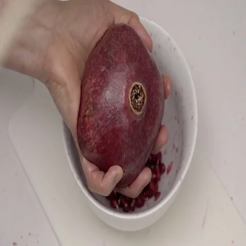 Banging the back of a Pomegranate to release the seeds.  4K UHD. Stock Footage 69699772