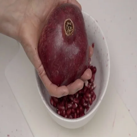 Banging the back of a Pomegranate to release the seeds.  4K UHD. Stock Footage 69700274