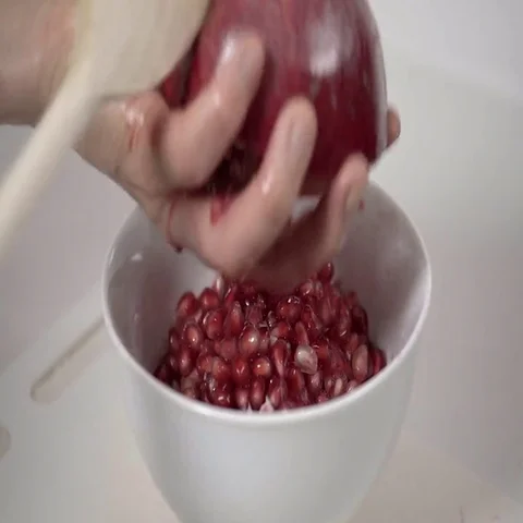 Banging the back of a Pomegranate to release the seeds.  4K UHD. Stock Footage 69703733