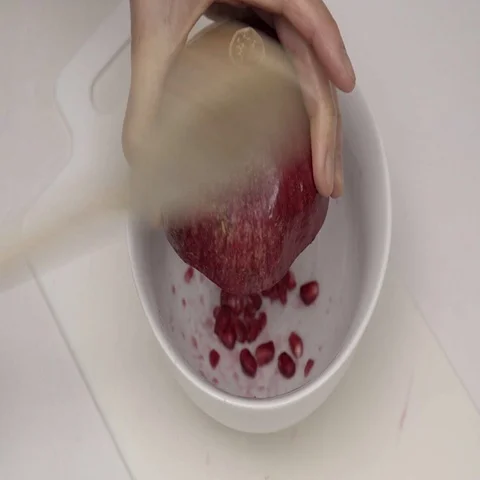 Banging the back of a Pomegranate to release the seeds.  4K UHD. Stock Footage 69705636