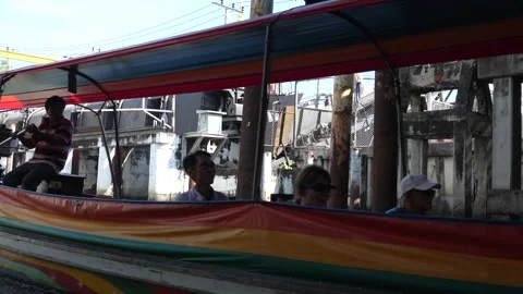 Bangkok canal longtail boat, operator steering near dock pilings and urban Stock Footage 320521453