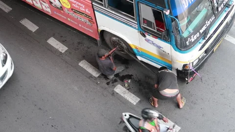 Bangkok, Thailand - 9/30/2020: Birds Eye View of 2 Men Changing A Flat Tyre Stock Footage