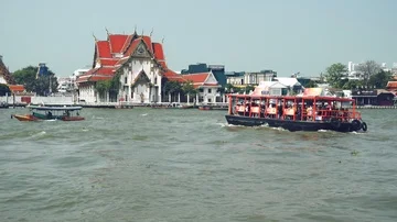 Bangkok - View of Chao Phraya river with boats and ancient temple in background. Stock Footage 85478162