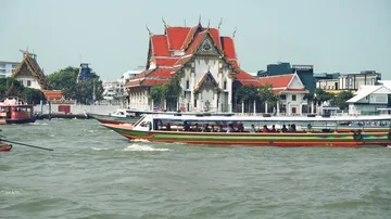 Bangkok - View of Chao Phraya river with boats and ancient temple in background. Stock Footage 85478239