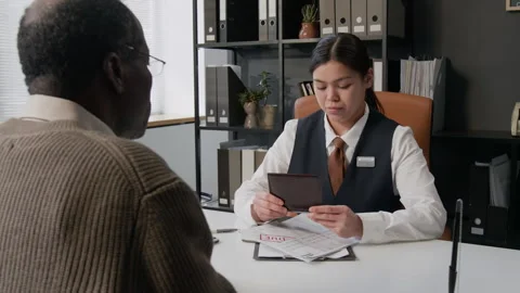 Bank Employee Handling Documents of Elderly Customer in Office Stock Footage 330965284