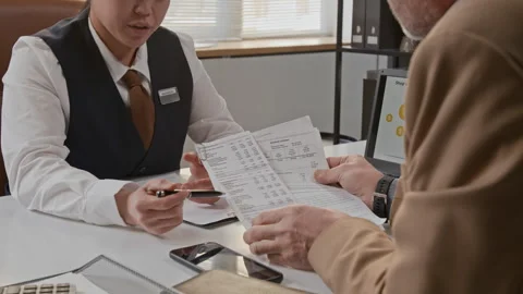 Bank Employee Pointing with Pen at Document Held by Man in Office Stock Footage 330970487