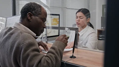 Bank Teller Helping Elderly Customer with Signing Documents in Bank Office Stock Footage 330967137