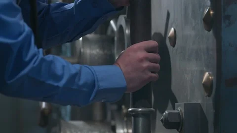 Bank Vault with heavy door on hinge closes, Guard turning, pushing large wheel Stock Footage