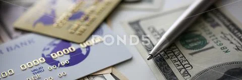 Banking plastic card and silver pen lying on big amount of US money Stock Photos