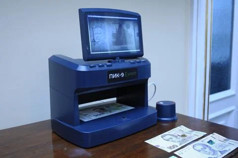 Banknote detector Expert working on a table, banknotes placed in receiver. Stock Photos