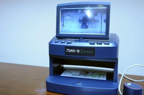 Banknote detector Expert working on a table, banknotes placed in receiver. Stock Photos