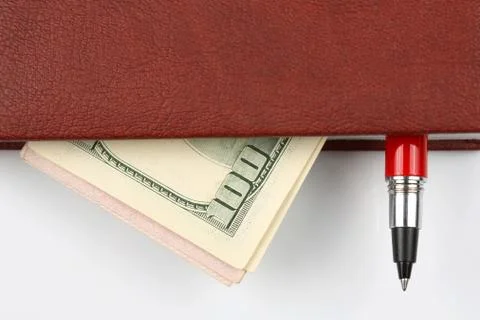Banknotes and a red pen lying inside the notebook. Stock Photos