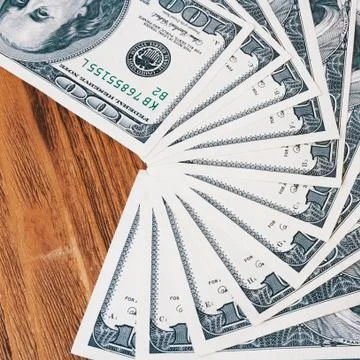 Banknotes of one hundred dollars spread out like a fan on the wooden boards. Stock Photos