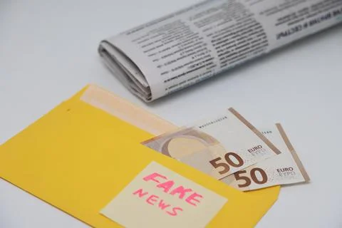 Banknotes in a yellow envelope on a light background. Fake news sticker on .. Stock Photos