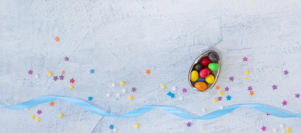 Banner with candy in the shape of an egg filled with multi-colored chocolates Stock Photos