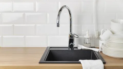 Banner with clean washed white tableware near black kitchen sink with a chr.. Foto stock