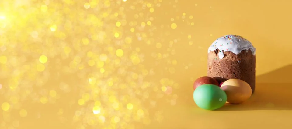 A banner with colored Easter eggs and a cake on a yellow background with a Stock Photos