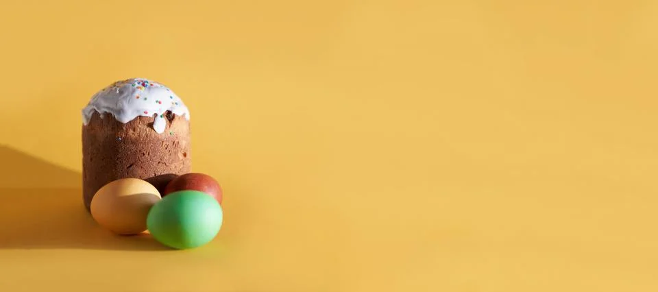 Banner colored Easter eggs on the background of Easter cake. Yellow background Stock Photos