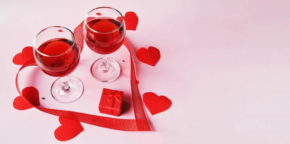 Banner on a light background two glasses of red wine, a red gift box with red Stock Photos