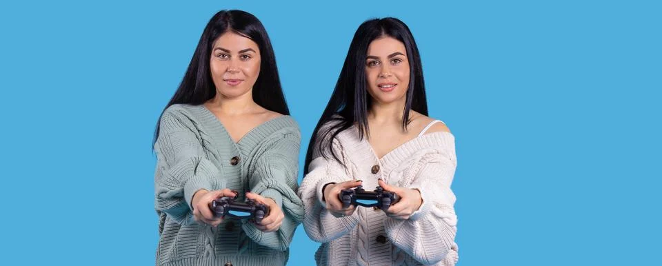 Banner, long format. Two nice twins female holding joysticks and are playing Stock-Fotos