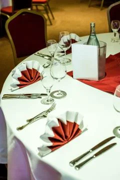 Banquet with red table setting tablecloth white dishes silver cutlery glasses Stock Photos