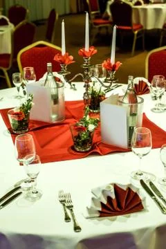 Banquet with red table setting tablecloth white dishes silver cutlery glasses Stock Photos