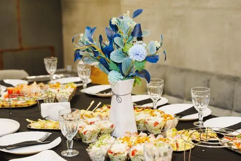 Banquet table setting with catering snacks and beautiful blue flower bouquet Stock Photos